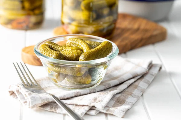 Small pickles. Marinated pickled cucumbers in bowl on checkered napkin.