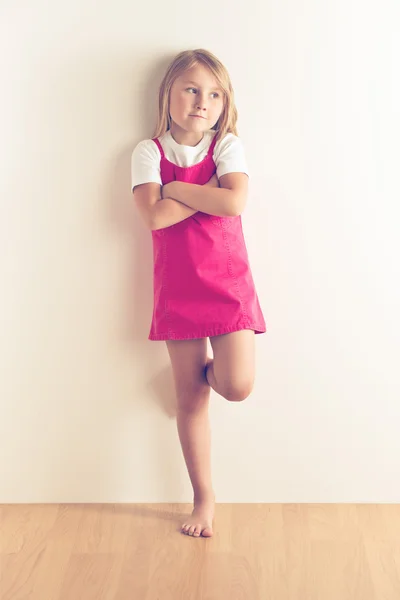 Little girl posing in front of a wall — Stock Photo, Image