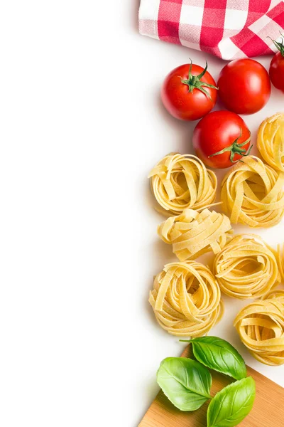 Pasta italiana tagliatelle, tomates y hojas de albahaca —  Fotos de Stock