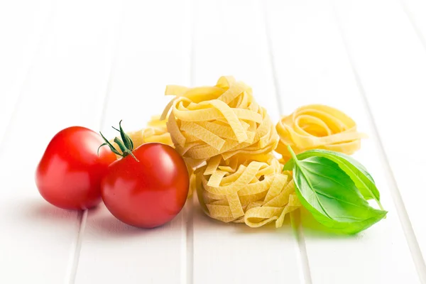 Pasta italiana tagliatelle, tomates y hojas de albahaca —  Fotos de Stock