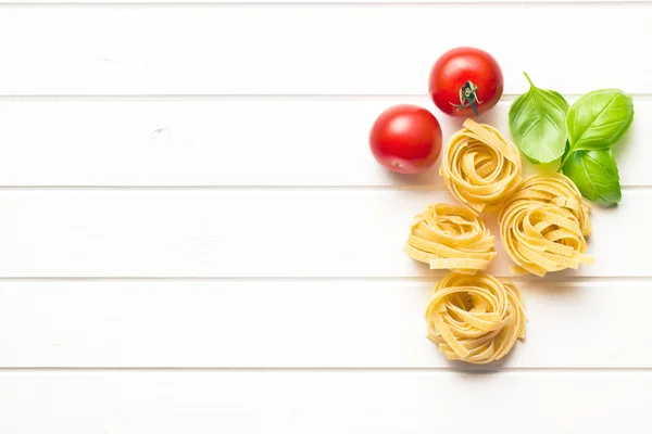 Macarrão italiano tagliatelle, tomates e folhas de manjericão — Fotografia de Stock