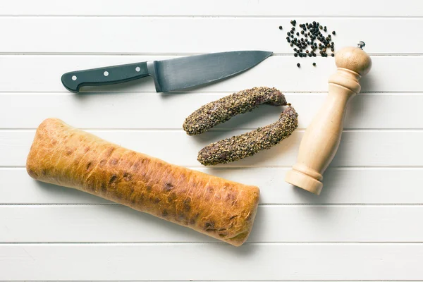 Sausages, ciabatta, knife and pepper mill — Stock Photo, Image