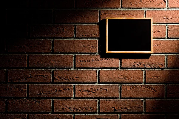 レンガの壁に掛かっている空の黒板 — ストック写真