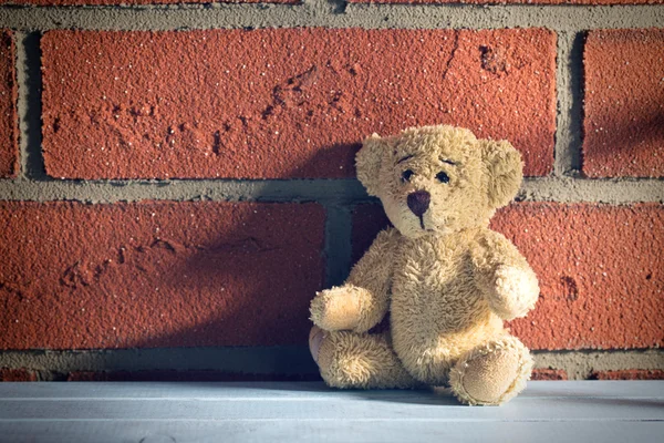 Плюшевий ведмідь сидить перед цегляною стіною — стокове фото