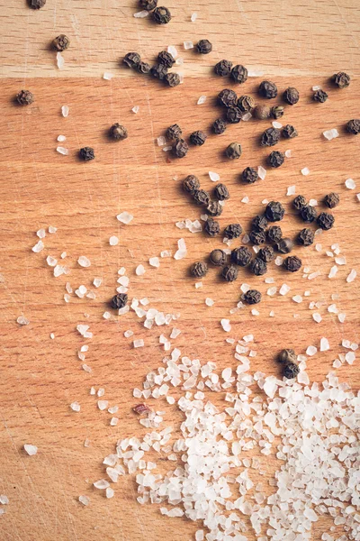 Salt crystals and black peppercorns — Stock Photo, Image