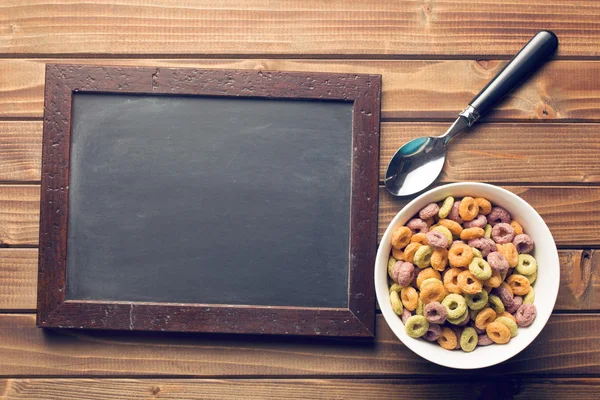 Chalkboard and colorful cereal rings in spoon — Stock Photo, Image