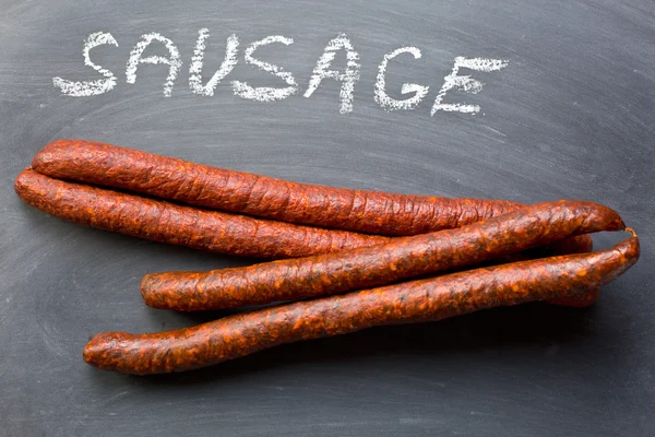 Dried sausages on chalkboard — Stock Photo, Image