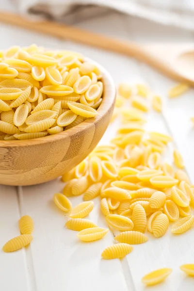 Uncooked italian pasta in wooden bowl — Stock Photo, Image