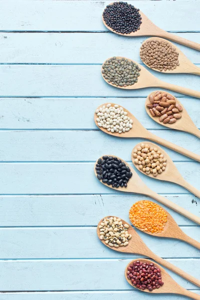 various dried legumes in wooden spoons