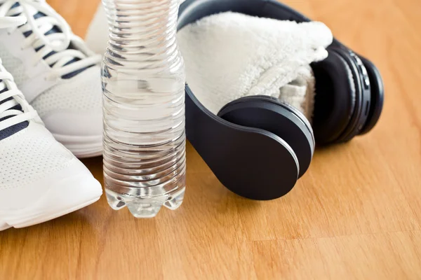 Concepto deportivo. auriculares, zapatos y agua en botella — Foto de Stock
