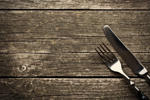 Widelec i nóż w starym drewnianym stole — Zdjęcie stockowe