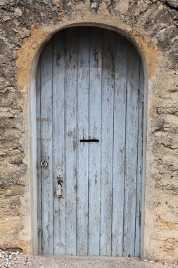 Eski taş duvardaki mavi kapı boyalı.