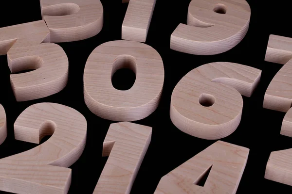 大きなランダムな木製の数字は黒の背景テーブルの上に置く コピースペースのある広葉樹の文字 — ストック写真