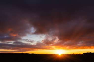 Kırsal günbatımı ufukta parlayan altın bir güneş ve üzerinde ağır bulutlarla. Norfolk İngiltere 'sinde halk manzarası yok.