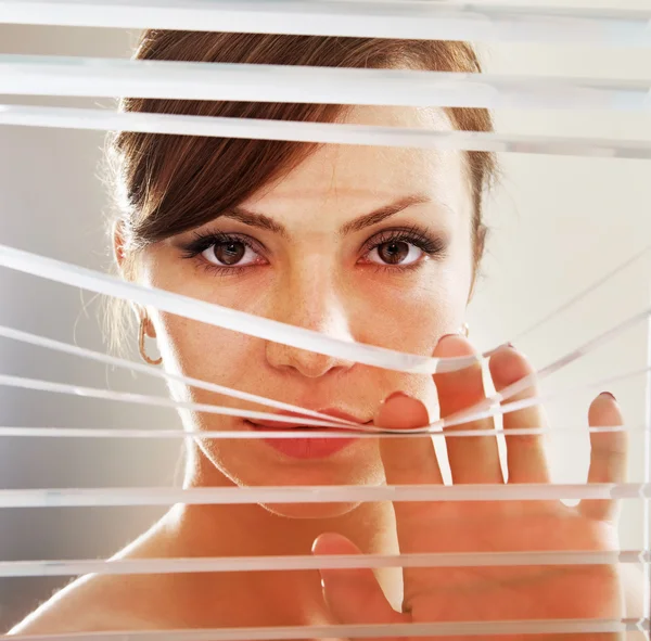 Vrouw merkt via blinds — Stockfoto