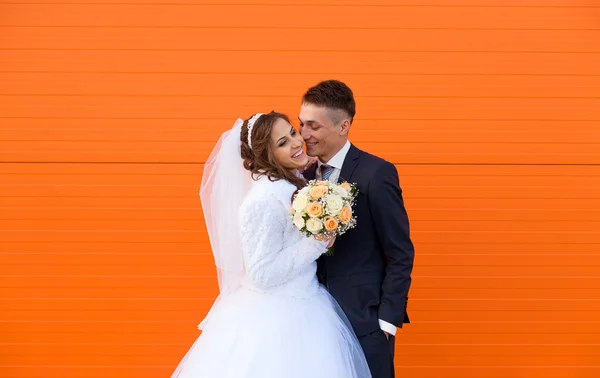 Bruid en bruidegom op oranje achtergrond — Stockfoto