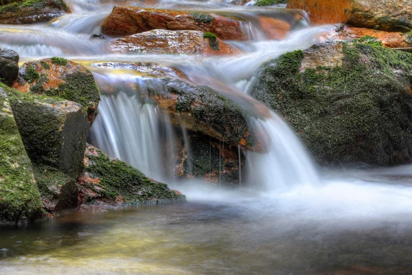 Longa exposição da água que flui sobre pedregulhos — Fotografia de Stock