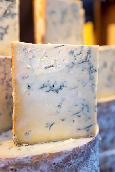 全体のスタックと市場での販売のためのスティルトンチーズをカット これは 特徴的な青い静脈を作成するために追加されたPenicillium Roquefortiを持っていた人気のある英語の青いチーズです — ストック写真