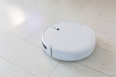 Robotik süpürge evde yerleri süpürüyor.