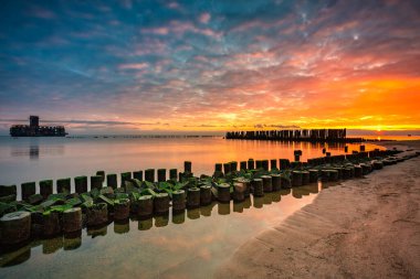 Plajda gün doğumu ve Gdynia 'daki Baltık Denizi' nde torpido platformu. Polonya