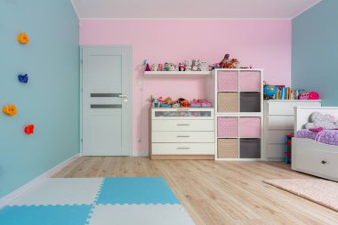 Turkuaz ve pembe çocuk oyun odası tırmanma duvarı ve oyuncakları olan