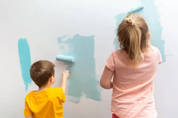 孩子们在房间的墙壁上涂着蓝绿色的胶辊 — 图库照片
