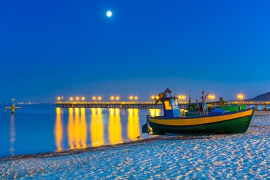 Baltic beach with fishing boat at night clipart