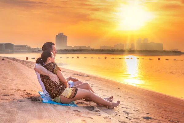 Paar beobachtet romantischen Sonnenaufgang am Strand — Stockfoto