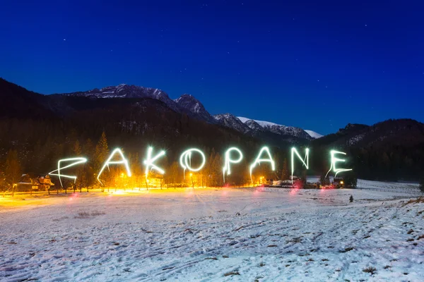 Signo de Zakopane bajo las montañas Tatra por la noche — Foto de Stock