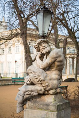 Lantern decorated by sculpture of satyr in Royal Baths Park of Warsaw clipart