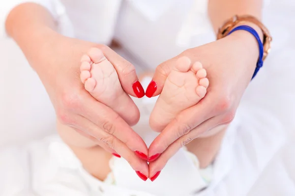 Bebis fötter i mor händer — Stockfoto