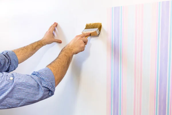 Handyman putting glue for a wallpaper