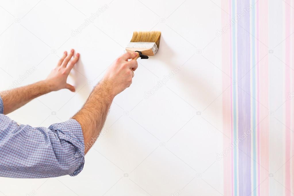 Handyman putting glue for a wallpaper