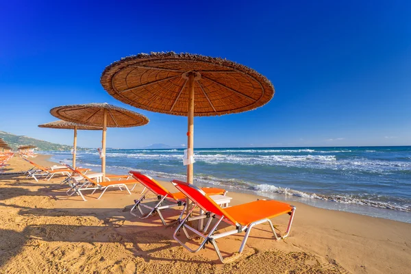 Parassóis e deckhcairs na praia de Banana da ilha de Zakynthos — Fotografia de Stock