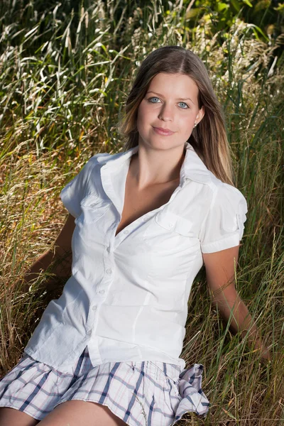 Beautiful young woman sitting in the grass — Stock Photo, Image