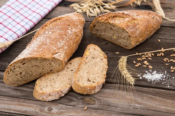 Pane rustico e frumento su un vecchio tavolo vintage in legno fasciato . — Foto Stock