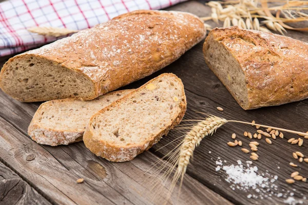 Pão rústico e trigo em uma velha mesa de madeira vintage pranchada . — Fotografia de Stock