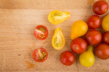 Ahşap kesme tahtası üzerinde kırmızı ve sarı kiraz domates