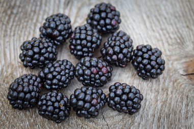 Many blackberries resting on the wooden table