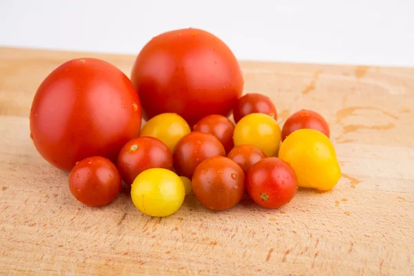 Tomates cherry rojos y amarillos en una tabla de cortar de madera — Foto de Stock