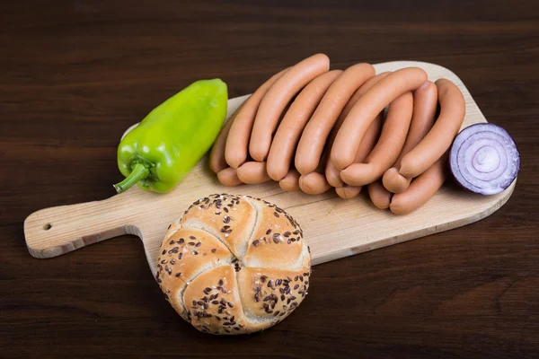 Salsicce disposte su tagliere con baguette — Foto Stock