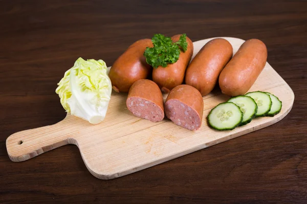 Embutidos dispuestos en tabla de cortar con lechuga —  Fotos de Stock