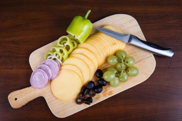 Sliced delicious cheese on wooden board — Stock Photo, Image
