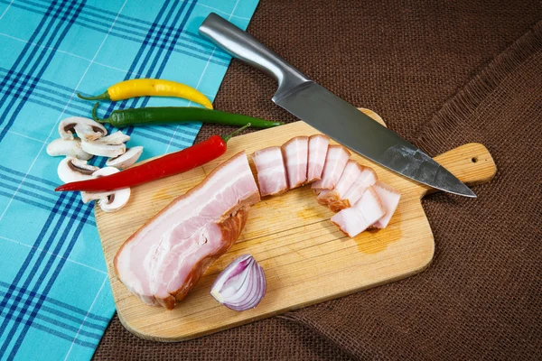 Bacon strips och chili peppers på trä skärbräda — Stockfoto