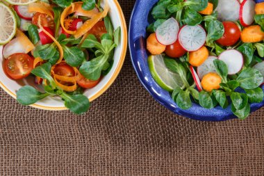 Jüt masa örtüsü üzerinde taze sebze salatası kaseler