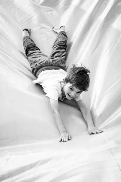 Sonriente niño jugando en la diapositiva inflable —  Fotos de Stock