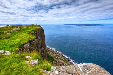Kuzey İrlanda, İngiltere 'de uçurumun kenarında sırt çantalı bir turist duruyor.