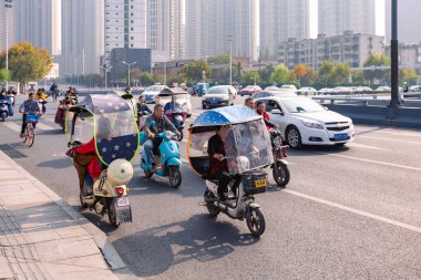 Renkli ön camlı elektrikli bisikletli insanlar kavşakta, Hefei, Çin.