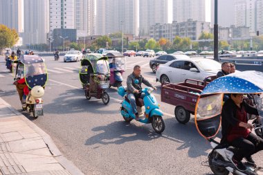 Renkli ön camlı elektrikli bisikletli insanlar kavşakta, Hefei, Çin.