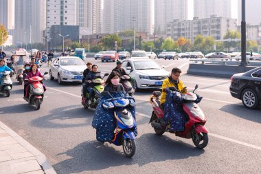 Renkli ön camlı elektrikli bisikletli insanlar kavşakta, Hefei, Çin.